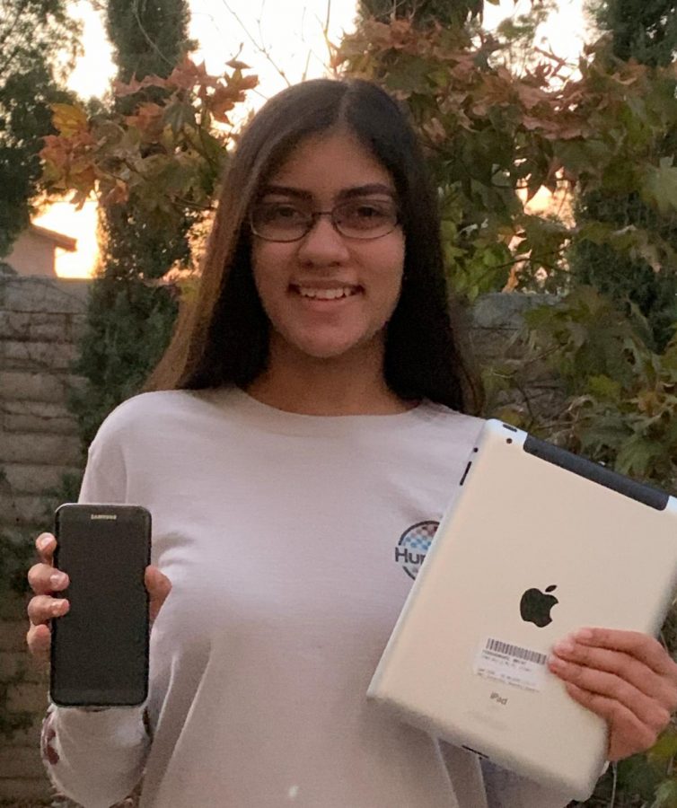 Tanya Bakshi (‘23) smiles, holding some of the many devices she has donated to help seniors.