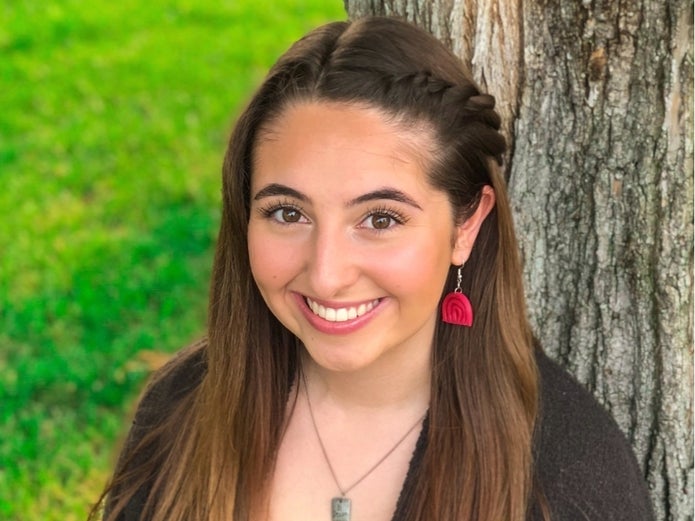 Maddie Stokes models one of her handmade clay earrings.