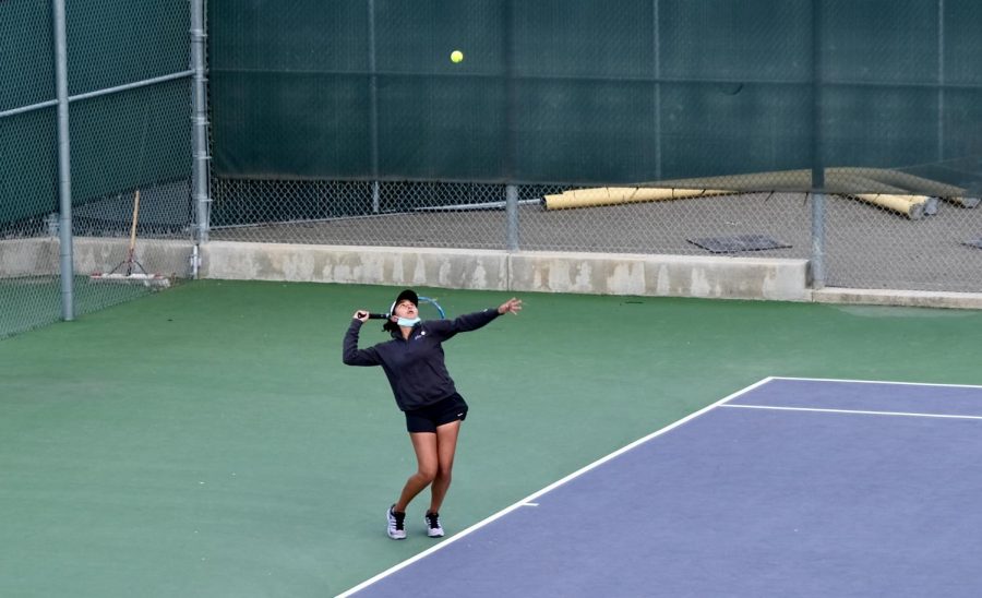 Knowing that focusing on the ball is key to tennis, Kruthika Gowda (22) serves an overhand with her concentration solely on the yellow object.
