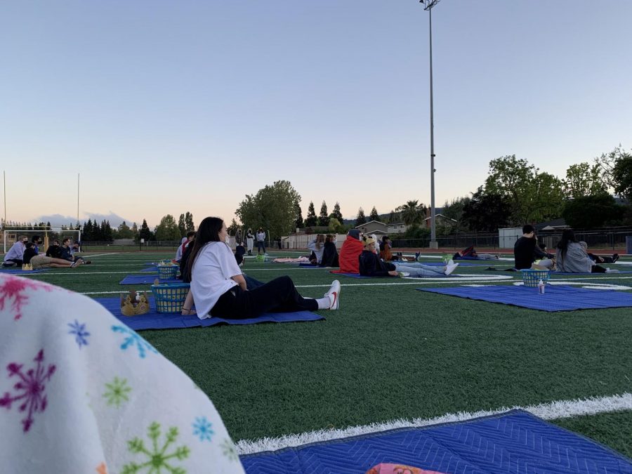 The picnic blankets are spread out across the football field and students are careful to wear masks while watching the movie Ferris Buellers Day Off.
