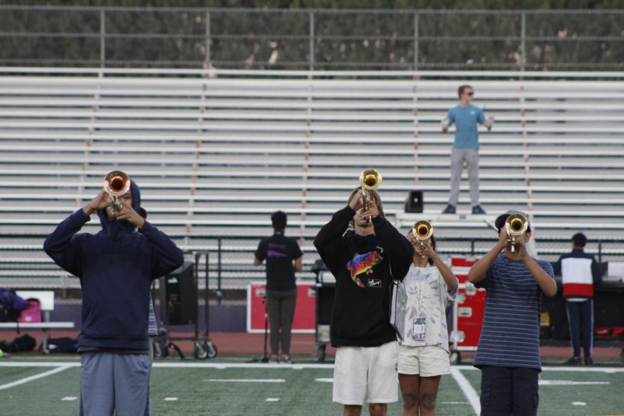 Trumpets performing with drum major in the background, making sure they're in their perfect spots.