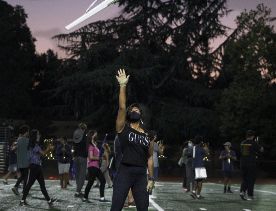 Colorguard member tossing her rifle in the air, clearly demonstrating the saying "practice makes perfect."