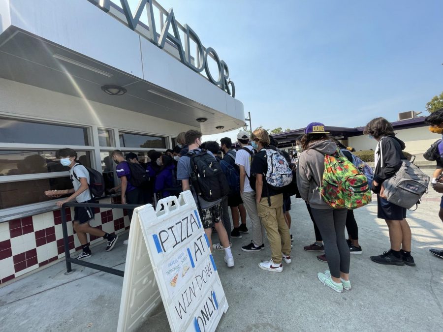 A huge group of students in the line squeeze their way to the small window to get their pizza.