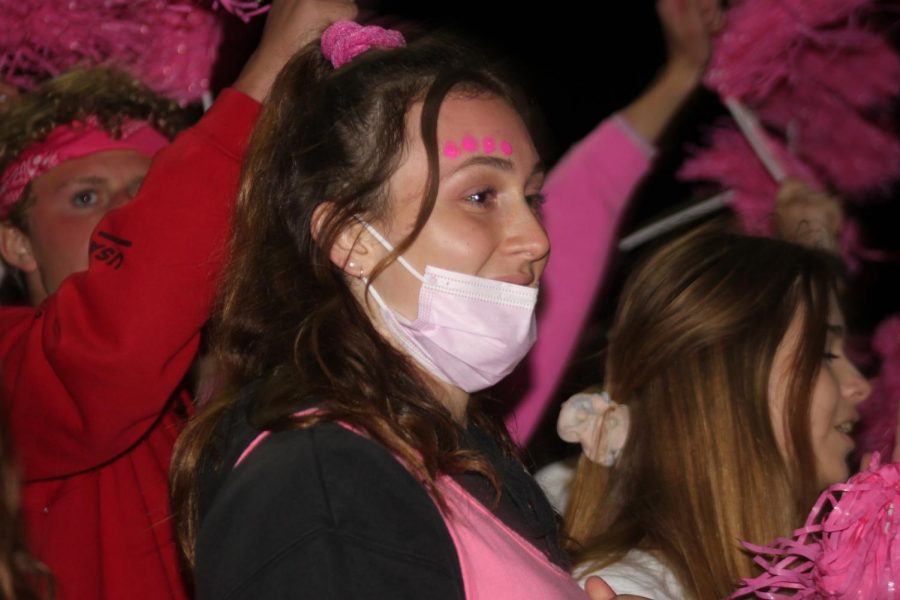 Nicole Belleville (23), all pinked-out, cheers on the varsity football team during the game
