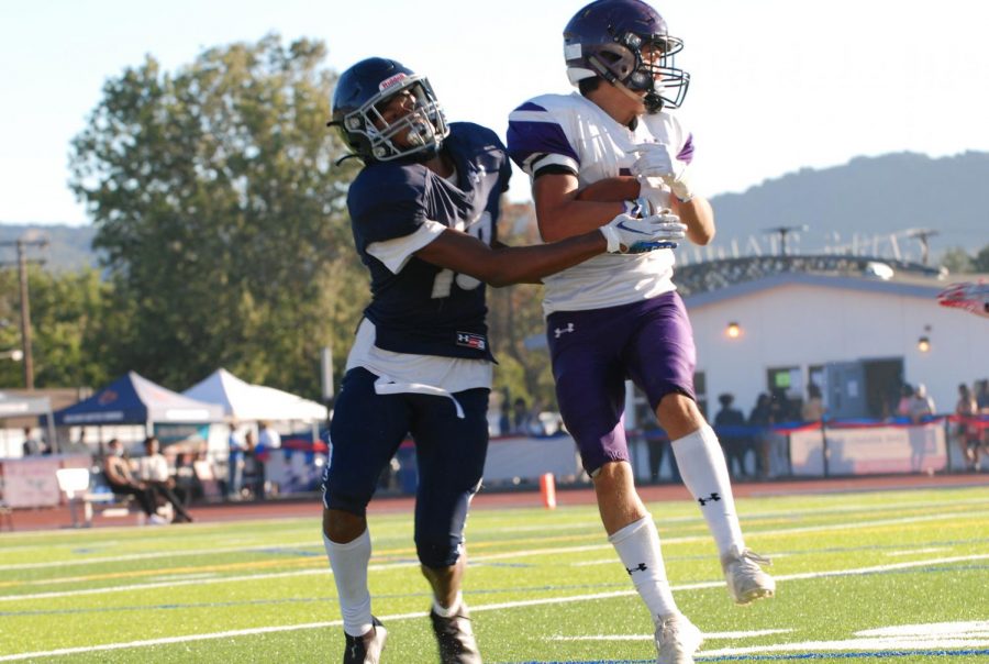 A rival player attempts to steal the football tucked underneath an Amador player's arm.