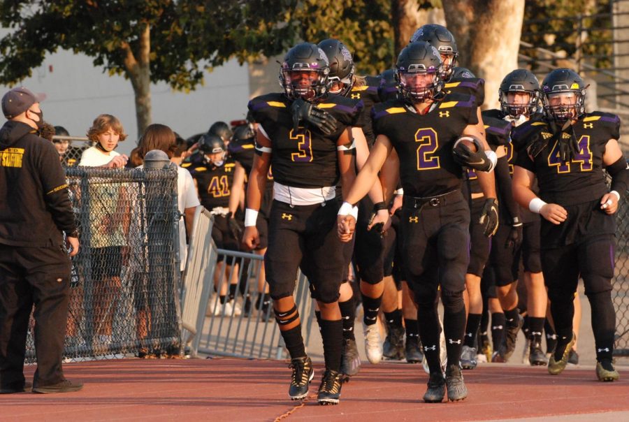 The varsity football marches onto the track.