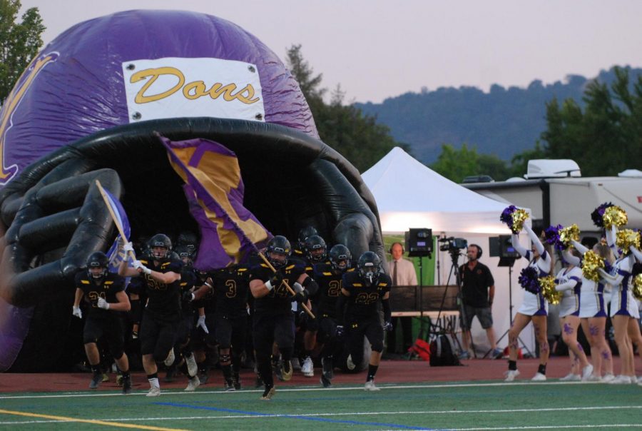 Amador players emerge from the dugout waving a flag to start the game.