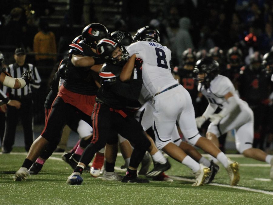 A group of football players huddle in a crush, trying to win the game.