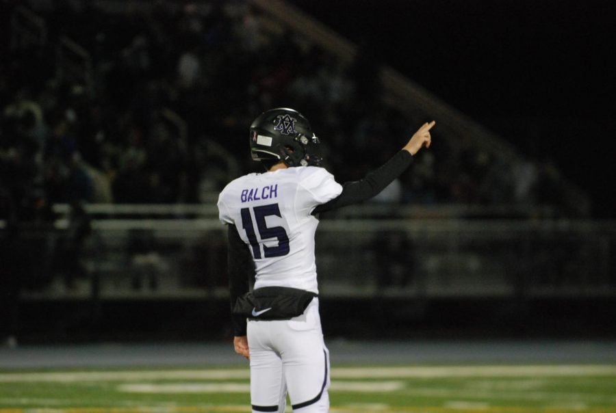 A football player signals a play to his team members.