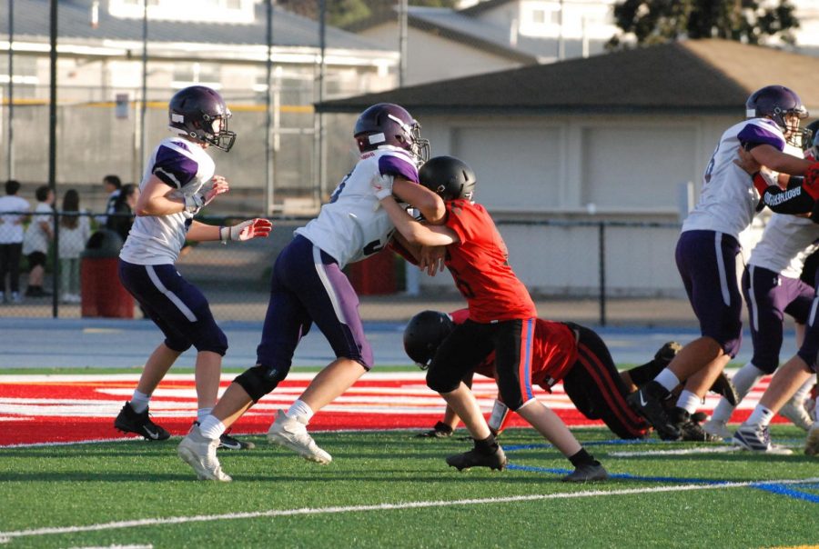 Two football players wrestle one another.