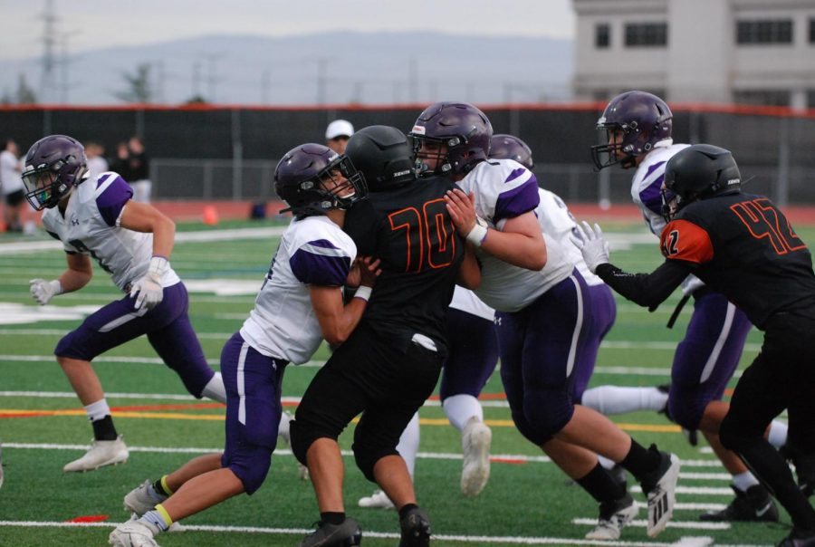 Caught in a crush, two Amador players hold back a rival player from running.