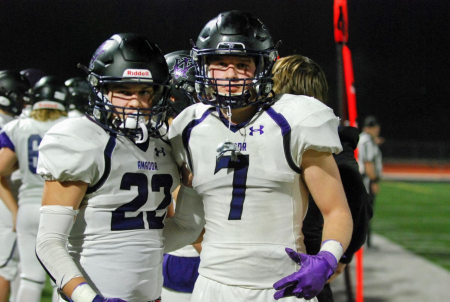 Two football players look at the camera, geared up and ready to defend.