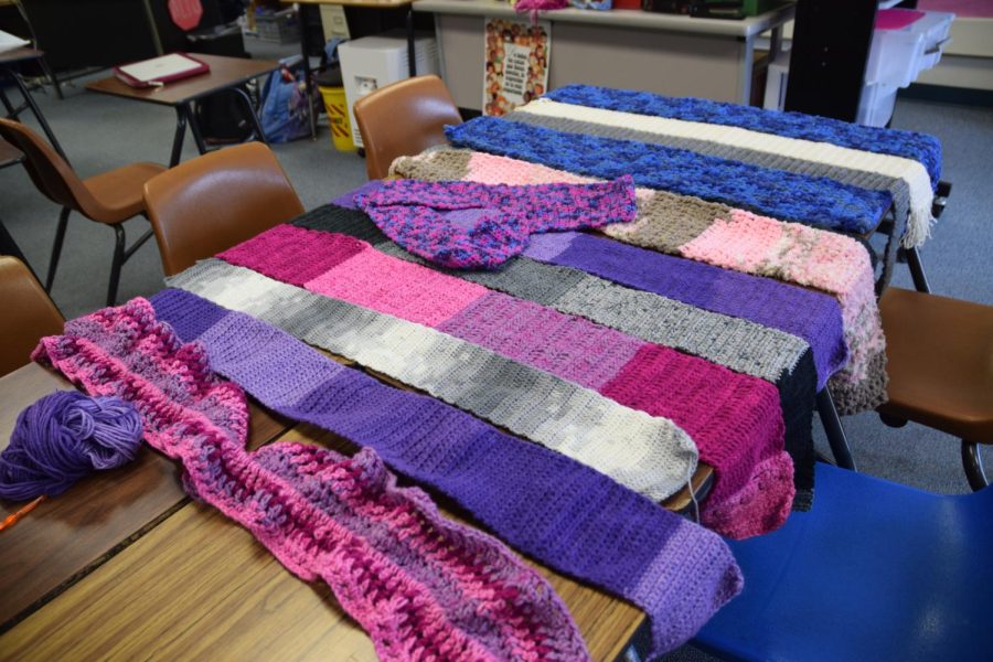 Members of the crotchet and knitting club lay their scarves along the table, perparing for their donation to the Tri Valley Haven center.