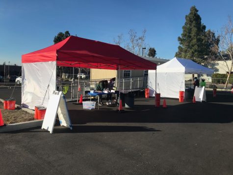 Inviting an inevitable chain of cars, Hart Middle School opens its back parking lot to testing tents for drive-in rapid antigen testing.