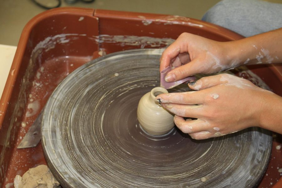 Using a pottery wheel and clay, students create vases.