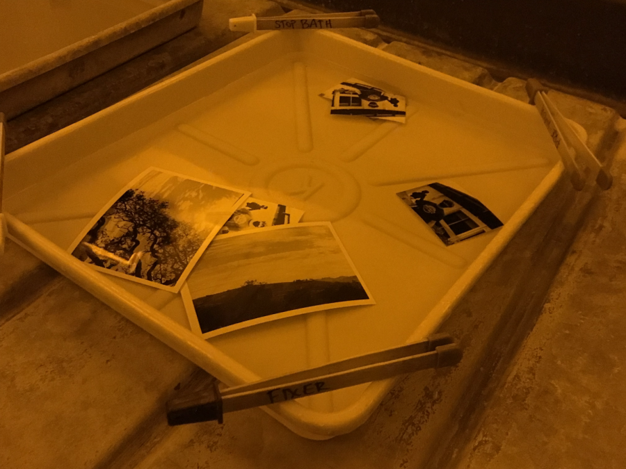 Photos of students using film cameras sit in chemical baths as the image develops.
