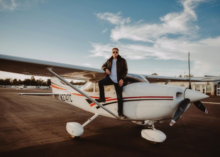 Tim Lester (22) leans on the side of a Cessna plane.