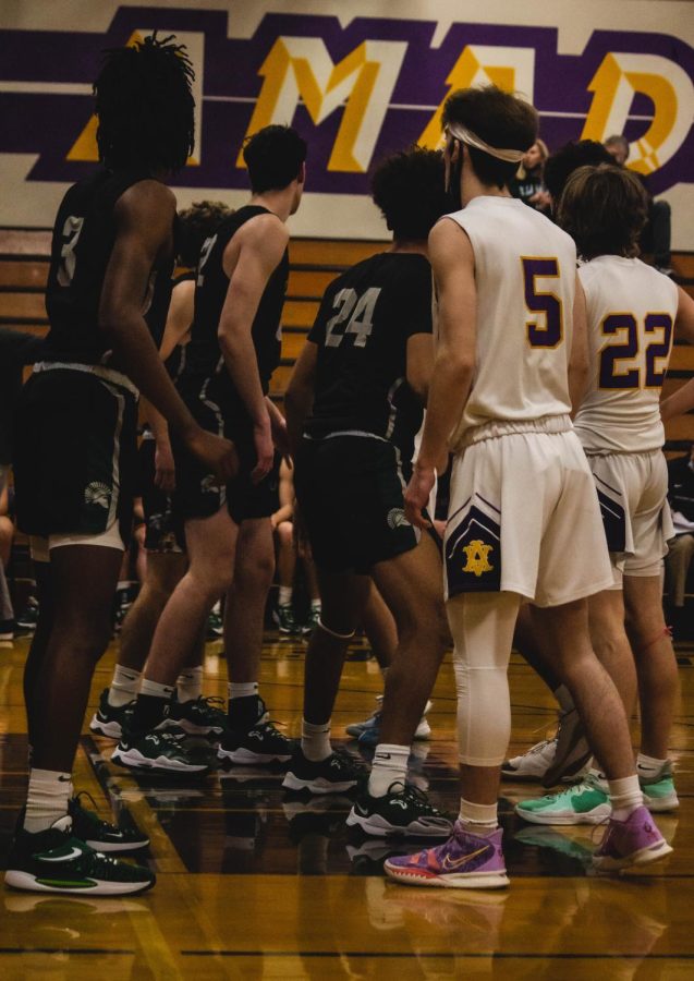 Amador and De La Salle players stand in contrast to one another, watching the basketball at the right of the court.