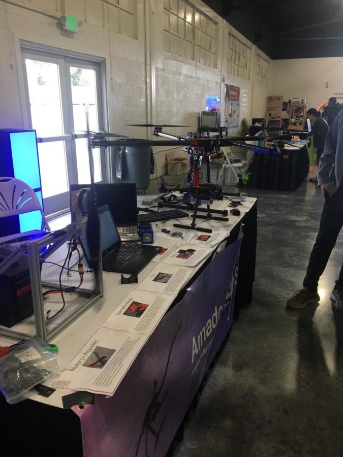 The AmadorUAVs' display table, featuring their drones and a propeller testing machine.
