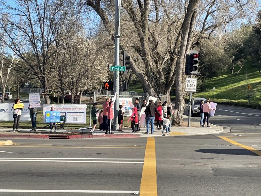 Pleasanton Parents and their children hold up signs as vehicles honk their horns in support.