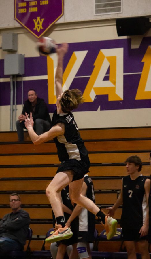 Bryce Nohava (23) spikes the ball in midair.