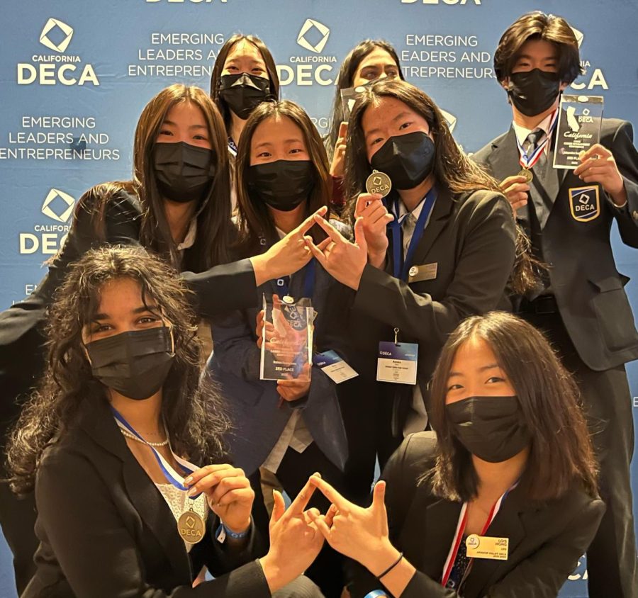 ICDC-bound AVHS students together for a group photo with the DECA hand sign as they hold their glass trophies and medal in hand.