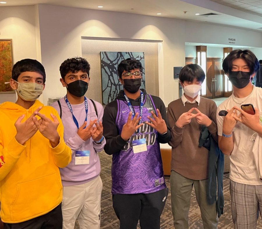 AVHS DECA students line up together with the DECA hand sign as they stand in the lobby of the Anaheim Marriott hotel.