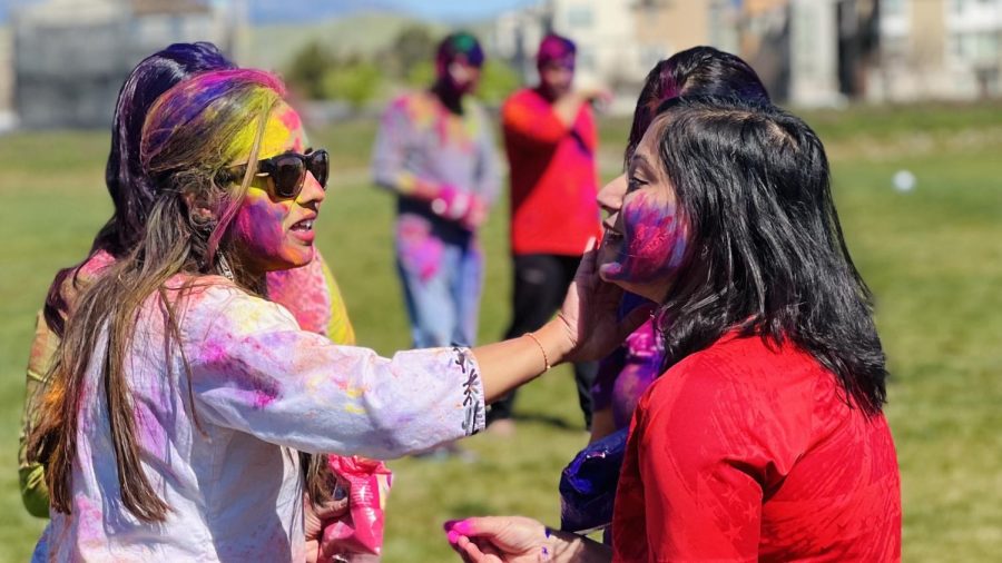 As a greeting, attendees of a Holi function smear colors on others’ cheeks while saying, “Happy Holi.