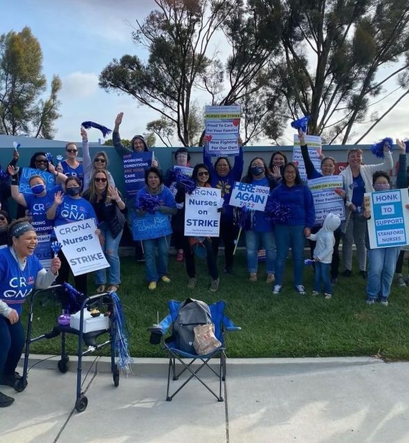 A group of nurses that are from the same branch come together and hold up home made signs to support the strike.
