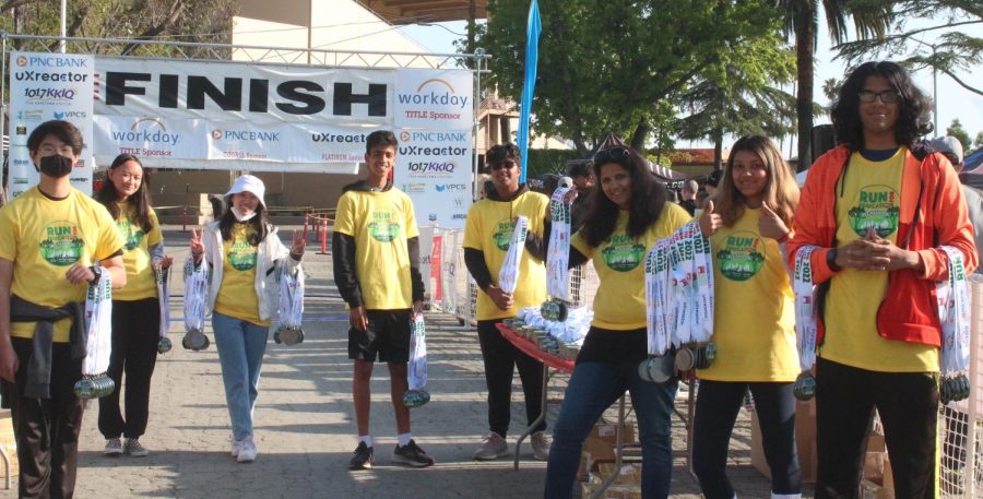 Volunteers at the finish line pass out medals to all the participants for their contribution to schools.