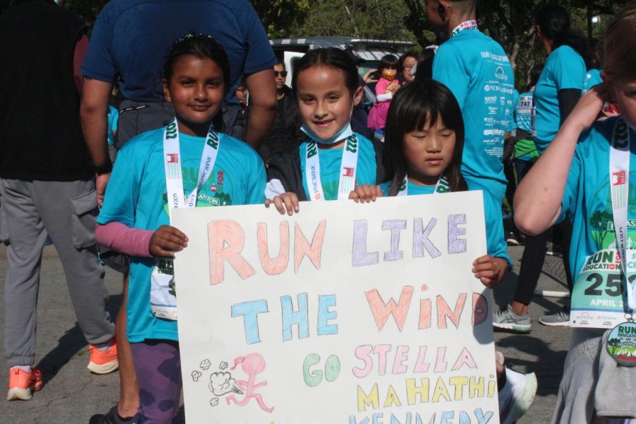 Three young 5K runners were cheered on by a sign by their families.