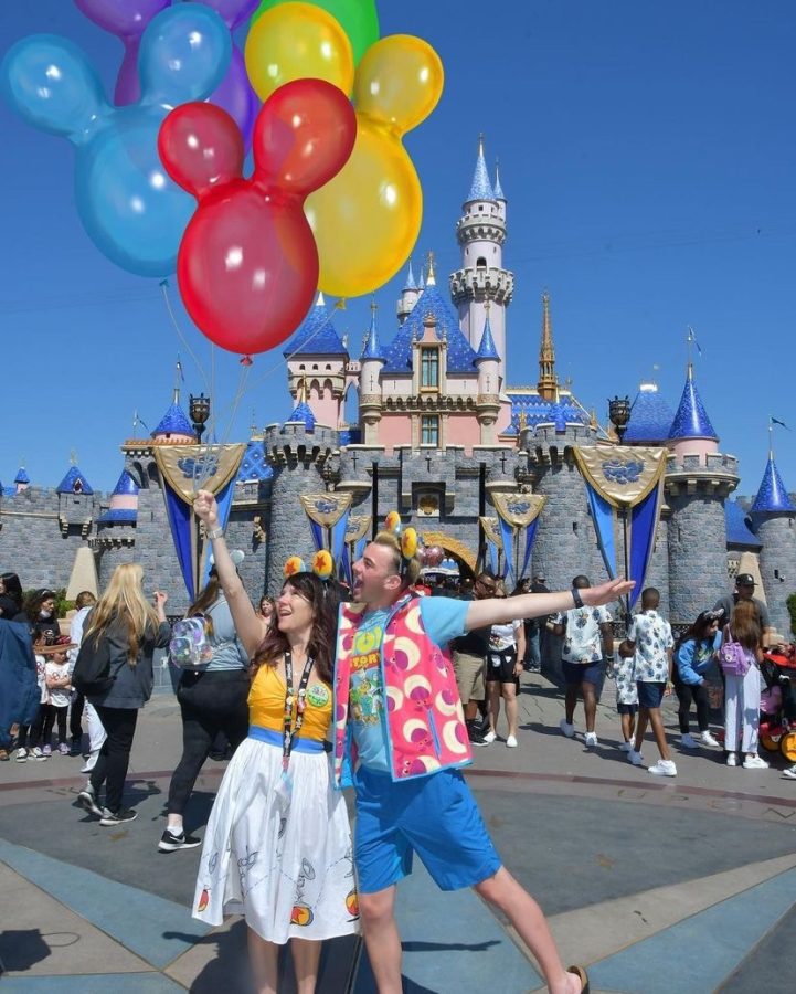 Brock Uhl (‘22) poses with Mickey Mouse balloons in front of the Sleeping Beauty Castle.