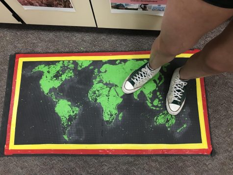While preparing to win the Amazing Race, a student stands on a handmade world map.
