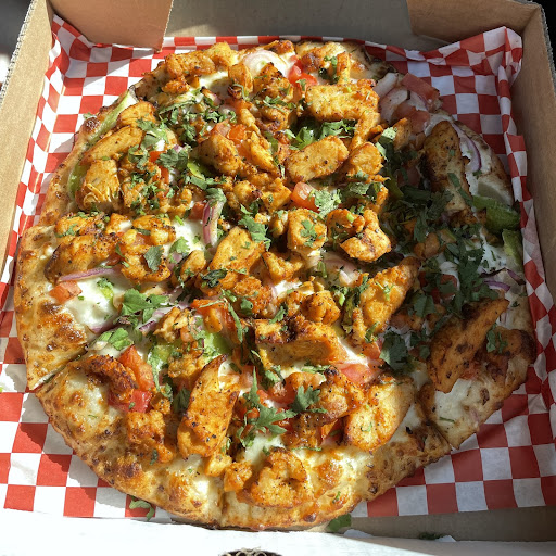 The signature Tandoori Chicken pizza is served on a crispy crust with white garlic sauce, tomatoes, bell peppers, onions, cilantro, and tandoori chicken.
