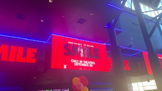 An advertisement for the movie in the Regal movie theater shows a person smiling, showing the theme of their whole movie.