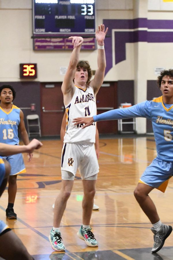 Colton Cash (23) shoots the ball as the opposing team tries to block him out.