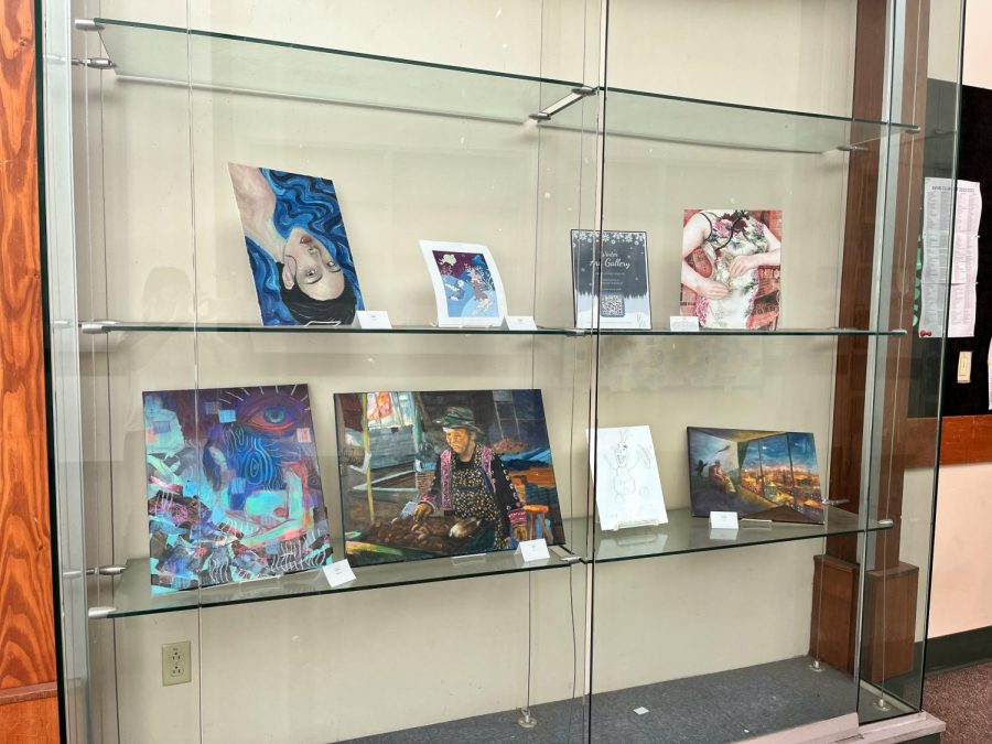Artwork is displayed on shelves and display cases in the library.
