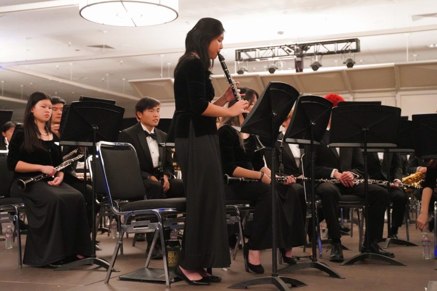 Soloist Tho Nguyen (‘23) stands and plays her clarinet while concentrating on her sheet music.