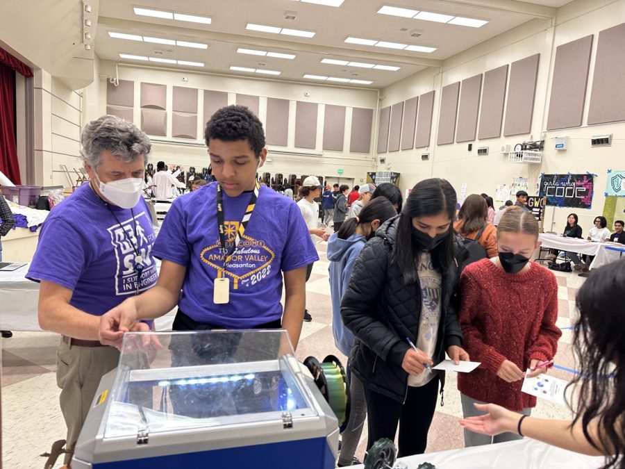 Engineering teacher Eric Dennis shows a student how to use a 3D printer.