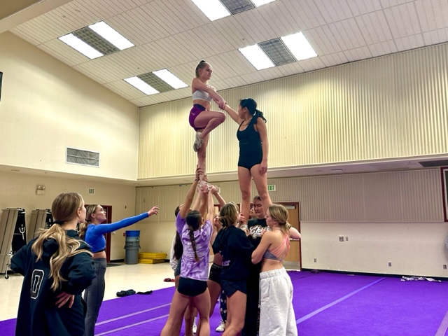 Maddie Ebel (24) holds on to Olivia Delgado (25) as she attempts an advanced stunt.