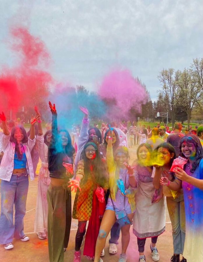 Students pose for a picture as colorful powder is thrown in the air.