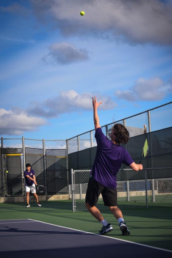 James Heeter (‘23), playing three singles, tosses the ball up high to hit a serve.