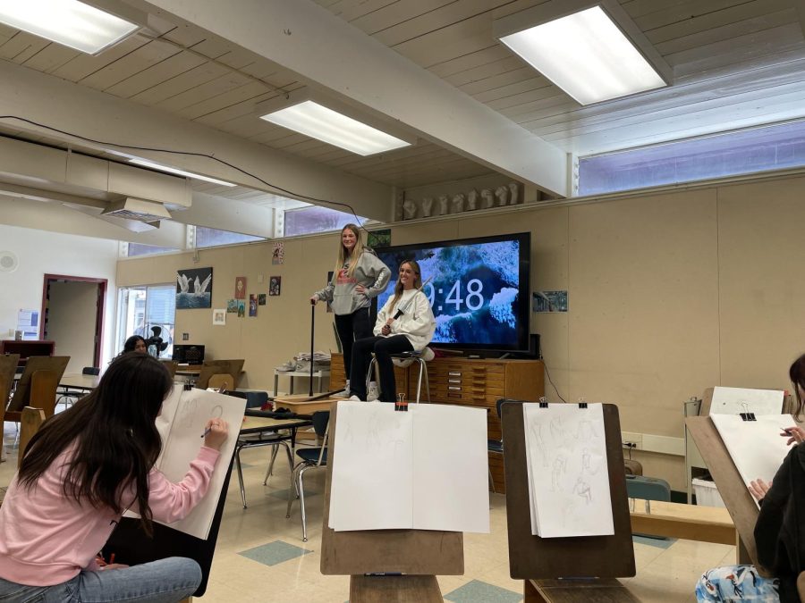 Art 1 students pose while their classmates use drawing horses to model their artwork.