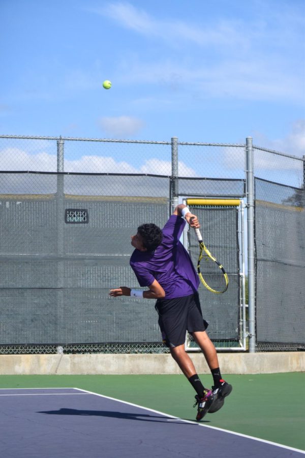 Playing line three singles, Aaren Sharma (25) leans forward to hit a serve.