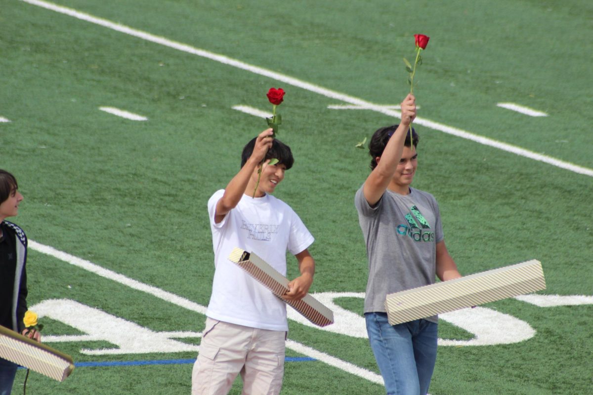 Freshmen Homecoming Court winners hold up their roses to show off to the crowd. 