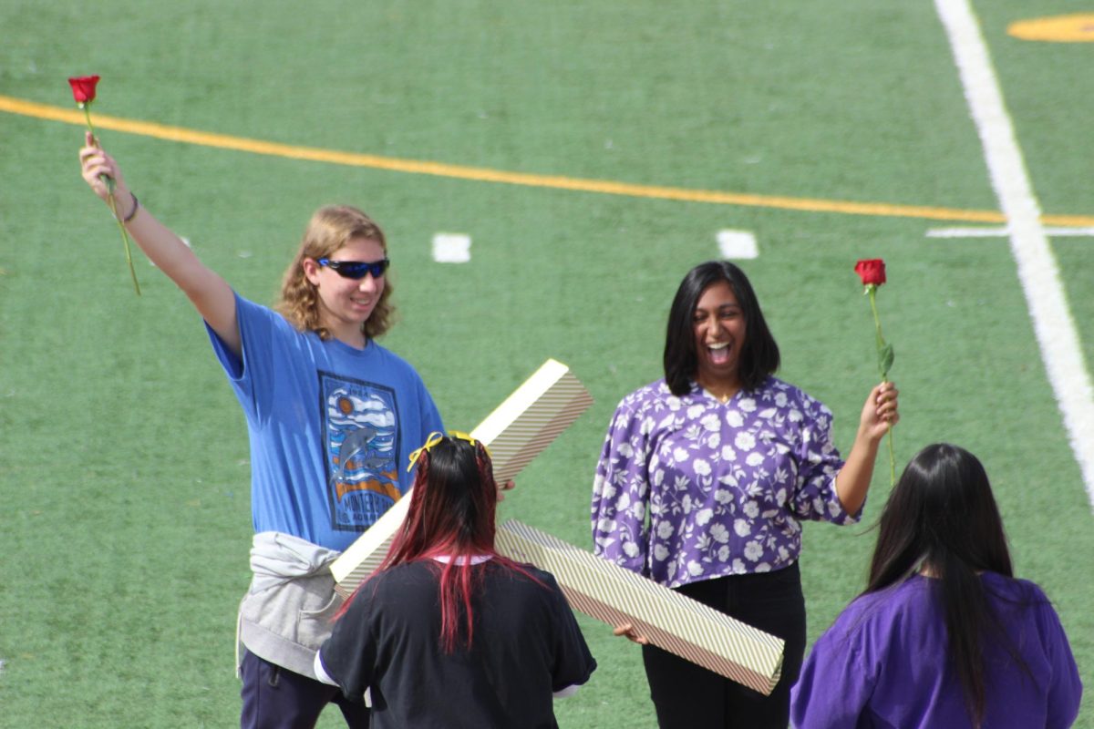 Parker Grendall (24) and Brinda Venkat (24) hold up their red roses.