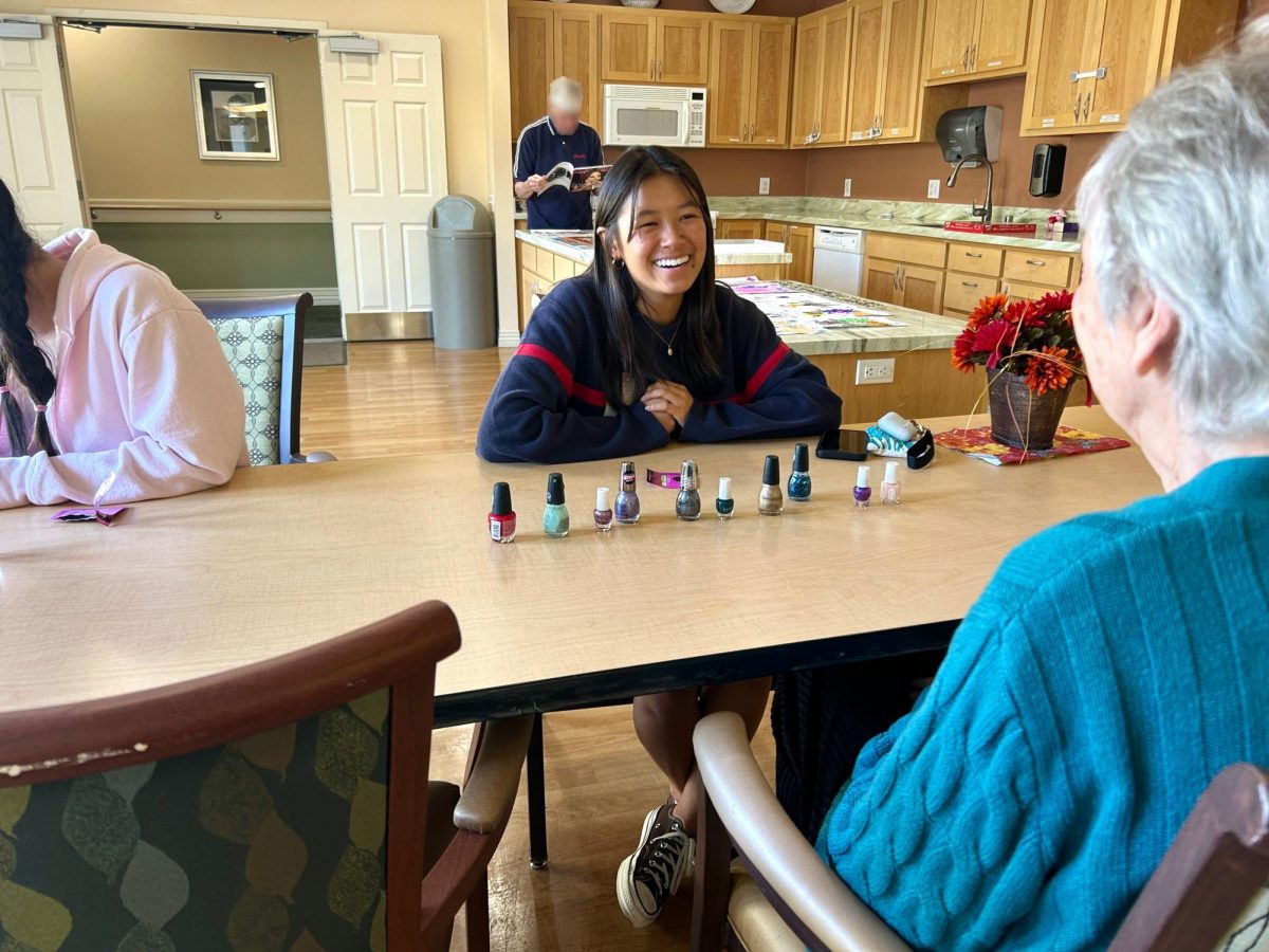 Maya Ng (25) sets out a display of nail polish colors for a senior.