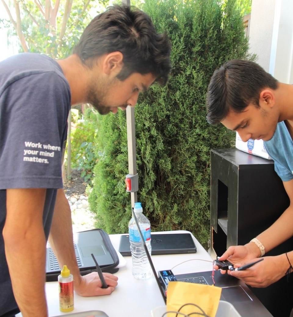 Aayush Gupta (24) works on debugging with his teammate at an UAV meeting.