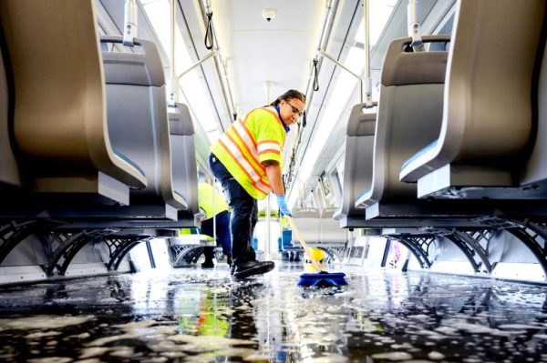 A cleaner thoroughly mops the floor of a train car.