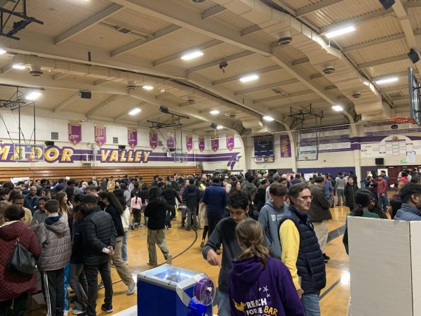 Teachers, students, and parents gather in the large gym for the Curriculum Fair.